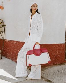 A woman wears a white lace pants set and canvas bag.
