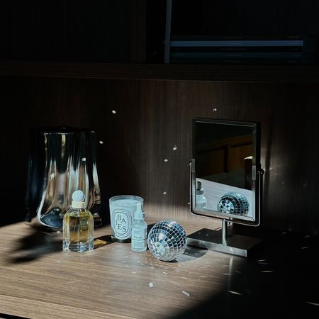 Photo of a candle, mirror, disco ball, and fragrance on a shelf