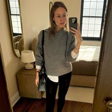 Nikki wears a black wool coat and white button-up with cashmere tights.