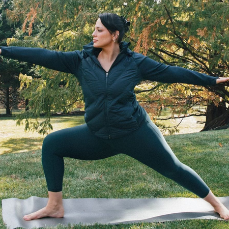 Model Ashley Graham working out and doing yoga in the best plus-size leggings outside on yoga mat.